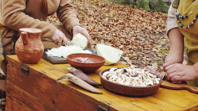 Hands of womens viking are cooking in the forest camp.