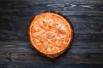 Appetizing freshly baked pizza with chicken and pineapple served on chopped wood, flat lay. Italian restaurant menu concept