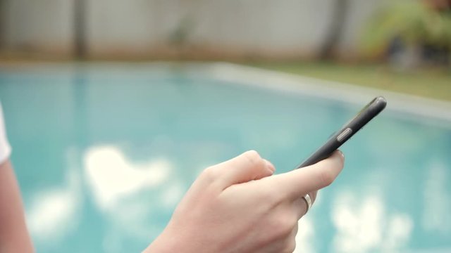 woman using a smart phone to take a photo of swimming pool background