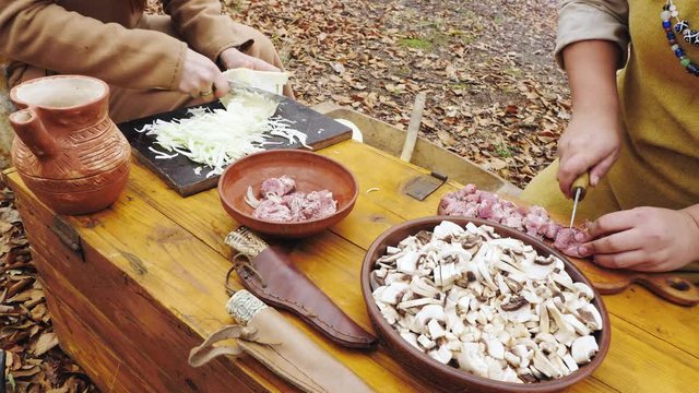 Hands of womens viking are cooking in the forest camp.