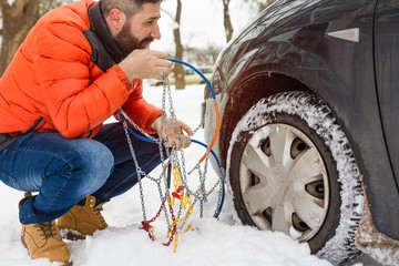 man putting snow chains on car tire