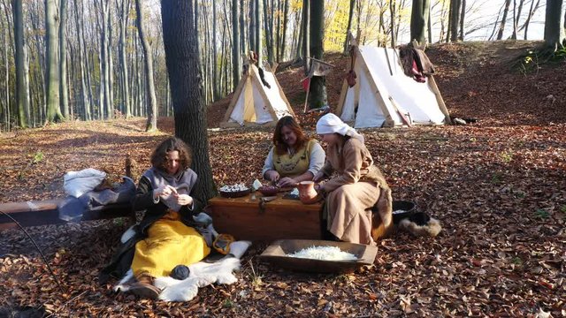 Portrait of Viking women prepare and knit in the forest camp