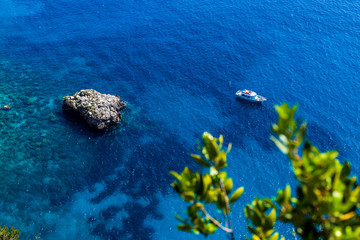 Fototapeta na wymiar Top view of a transparent water surface with rocks on a lonely boat in a summer sunny day- beautiful nature vacation background.