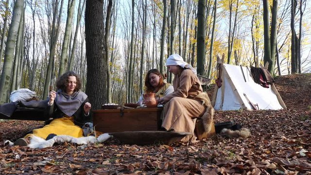 Portrait of Viking women prepare and knit in the forest camp