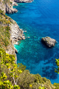 Rocky coastline and turquoise sea surface with rocks. Capri Island Italy - natural and travel background