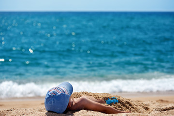 Fototapeta na wymiar Boy is laying on the beach sand.