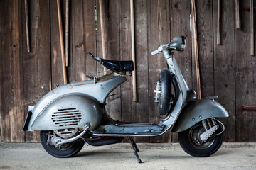 Barnfind oude, roestige, gebruikte Italiaanse motorscooter op houten muur
