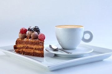 The piece of chocolate pie with wild berries served with the cup of exellent capucino