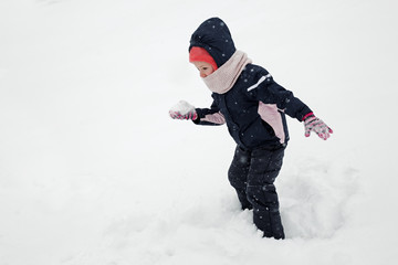 Fototapeta na wymiar child playing snowballs at winter park