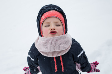 little girl child standing at winter park. Looking camera blowing kisses.