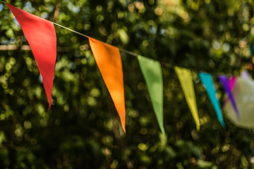 Colorful paper bunting flags hanging for trees at a summer party