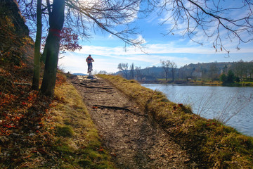Cycling on the river bank. Silhouette of woman riding bicycle. Active life, sport on the weekends. Sunny autumn.