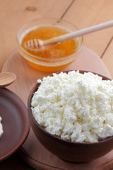 Cheese, fresh cheese and sour cream in pottery, honey, goat cheese for breakfast, healthy eating, healthy dairy products, cheese and cream in rustic style, minimalist, copy space, wooden board