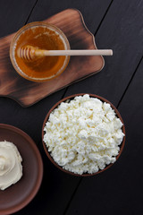 Cheese, fresh cheese and sour cream in pottery, honey, goat cheese for breakfast, healthy eating, healthy dairy products, cheese and cream in rustic style, minimalist, copy space, wooden board