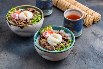 Rice and beef bowls with tea, concrete background