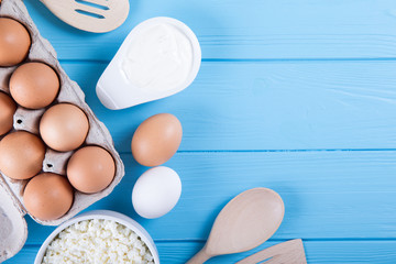 Dairy products on blue wooden table. Sour cream, milk, cheese, egg,  and butter.