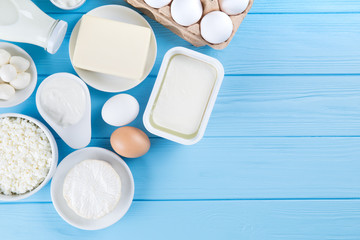 Dairy products on blue wooden table. Sour cream, milk, cheese, egg,  and butter.