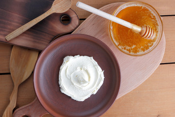 Sour cream, cream, fresh sour cream in pottery on a wooden background, dairy products and honey, wooden board, French breakfast, healthy food, sour cream and honey in a rustic style, minimalism, copy 