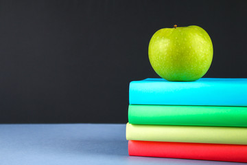 A pile of books and stationery on a chalkboard background. Work desk, education, school.