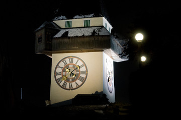 The clock tower of Graz illuminated during a cold winter night in the Styrian capital. The construction is one of the city's most well known symbols