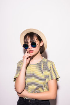 Pretty hipster teen girl in sunglasses and a straw hat isolated on white background