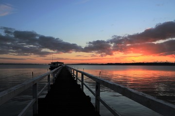 malerischer Sonnenaufgang an einer Seebrücke am Meer, Konzept Seebestattung, Trauer, Abschied