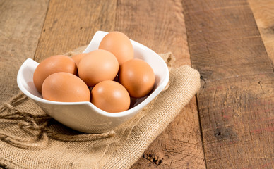 Freshly laid organic eggs in bowl on wooden bench