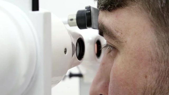 Patient in ophthalmology clinic. Man looks in synoptophore - ophthalmic Instrument, used for diagnosing imbalance of eye muscles and treating them by orthoptic methods, for treatment of strabismus