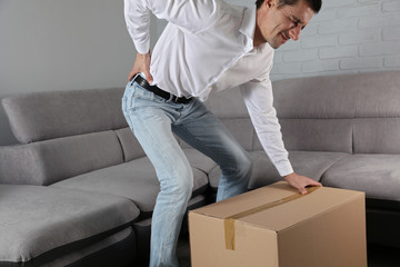 Man suffering from back pain moving boxes in his new house . Muscle spasm, rheumatism. Pain relief,...