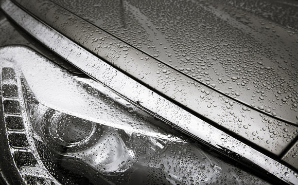 detail of a headlight of a modern car with rain drops