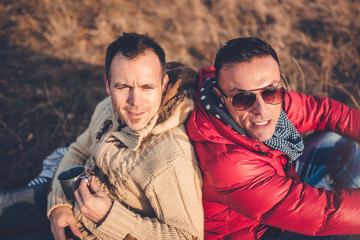 Gay male couple laying on blanket in grass