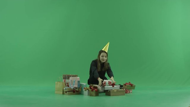 Young woman looks inside shopping bags, green chroma key background