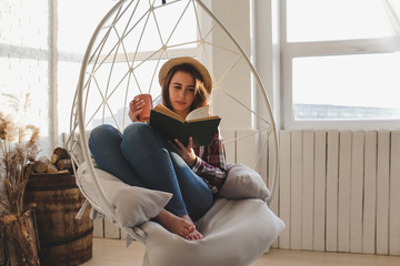 Girl relaxes reading a book and drinks tea.