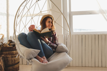 Girl relaxes reading a book and drinks tea. - obrazy, fototapety, plakaty
