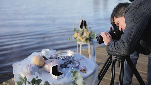 Cameraman with camera on tripod at sunny autumn day outdoors shooting wedding decoration