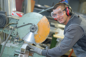 Portrait of worker by industrial circular saw