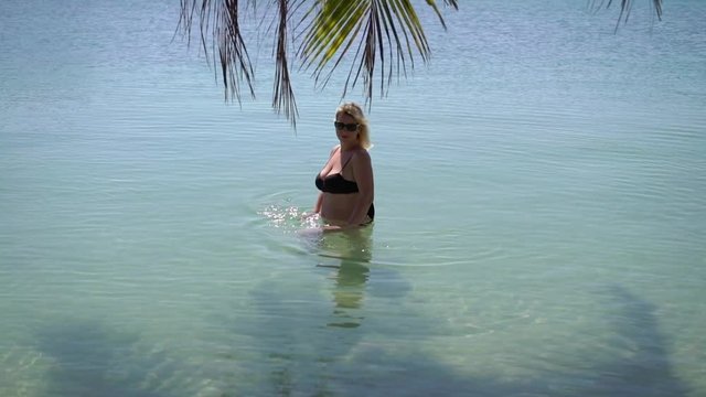 Young woman in black bikini in a sea at the beach