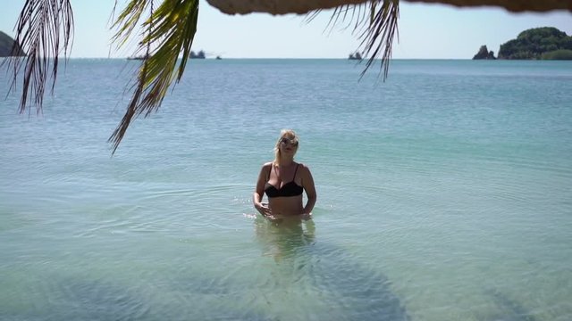 Young woman in black bikini in a sea at the beach