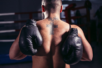 Young muscular man boxer. Boxing gloves slung over his shoulder