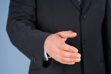 Obraz premium Closeup of a businessman in suit giving hand for handshake