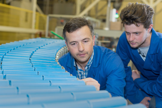 engineers looking at rolling conveyor belt in factory