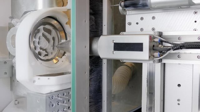 Processing of carving out shape of human teeth in modern dental hardware in workroom close-up