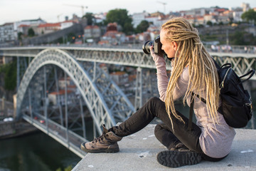 Young woman with camera on the viewing platform opposite the Dom Luis I bridge across the Douro river in Porto, Portugal.