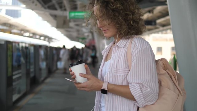 Female Commuter Using Mobile Phone While Waiting For Train