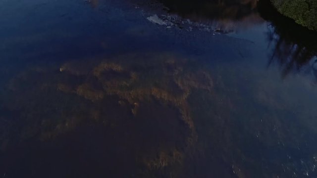 Aerial view of Glen Etive's lake with freezing water and thin ice and surrounding mountains, Scottish highlands, UK.