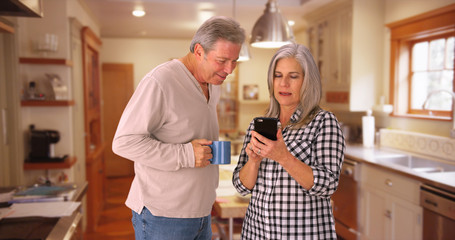 Elderly white couple reading looking at smartphone