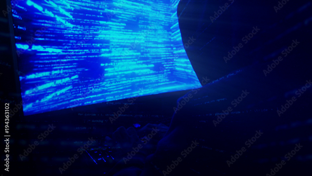 Poster a man hacker in a hood in a dark room works with the program code