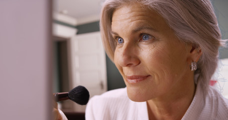 Lovely mature caucasian woman applying makeup