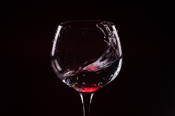 Red wine splashing out of a tall wine glass © bodiaphoto