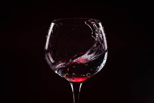Red wine splashing out of a tall wine glass